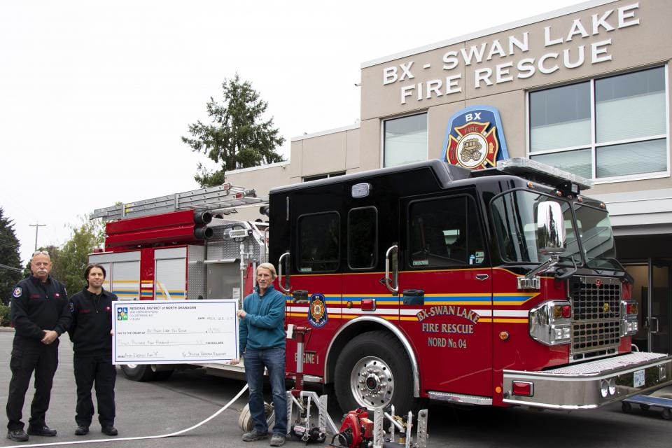 People presenting cheque in front of fire truck